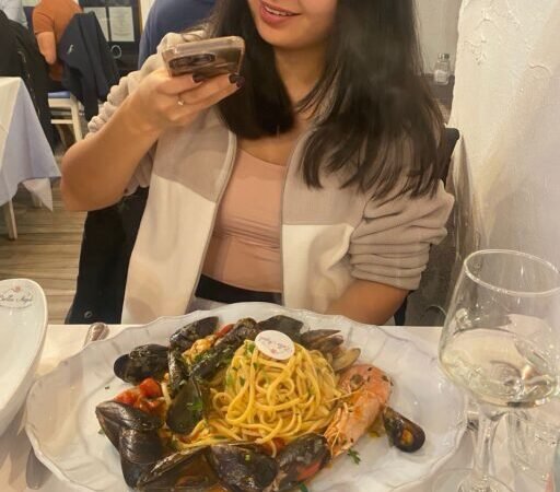 Yerkezhan taking a photo of seafood pasta at Bella Napoli in Bergamo, Italy